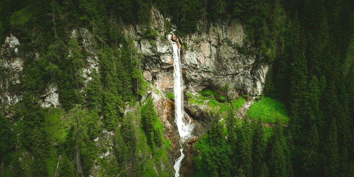 Waterfall flowing down rocky cliffs surrounded by dense green forest
