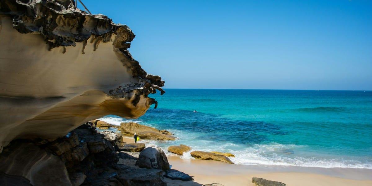 Rocky coastline and sandy beach with turquoise ocean waves in Oceania
