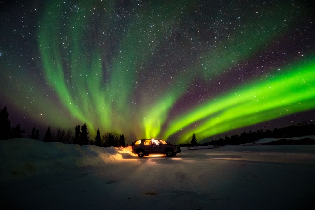 Bright green northern lights Aurora Borealis over a frozen Alaska landscape.